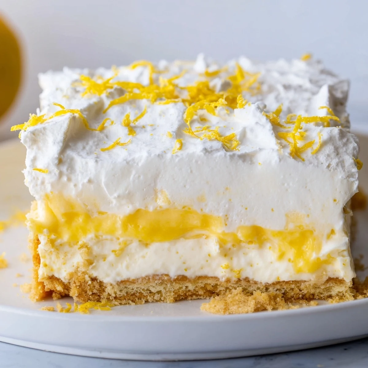 Golden square of lemon lush cake with creamy layers topped with white whipped cream