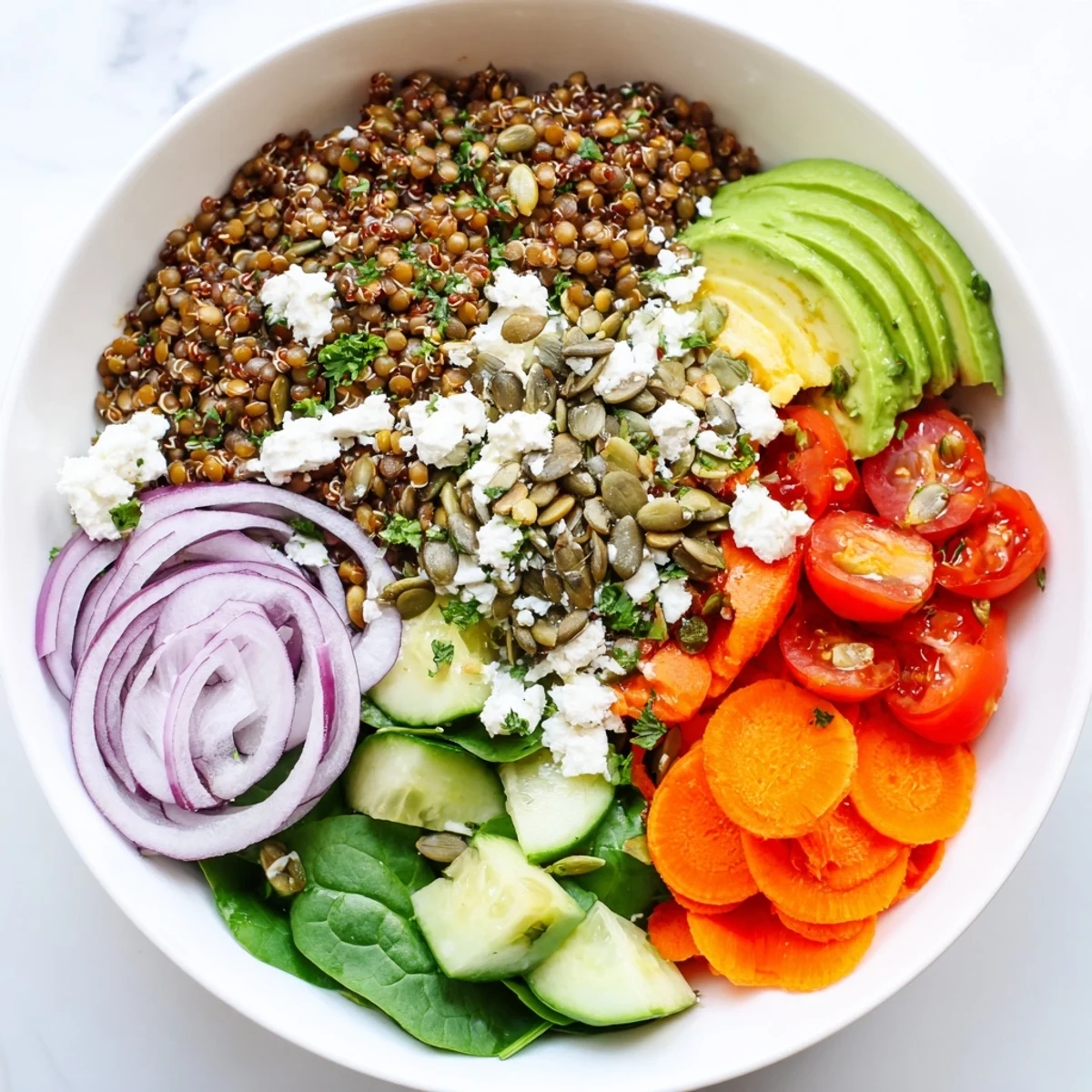 Colorful lentil grain bowl topped with fresh vegetables, avocado slices, and herbed dressing