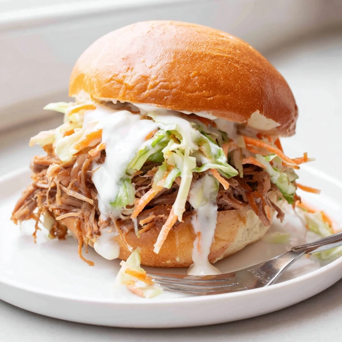 Tender shredded lamb shoulder dripping with tangy Alabama white sauce on soft golden slider rolls