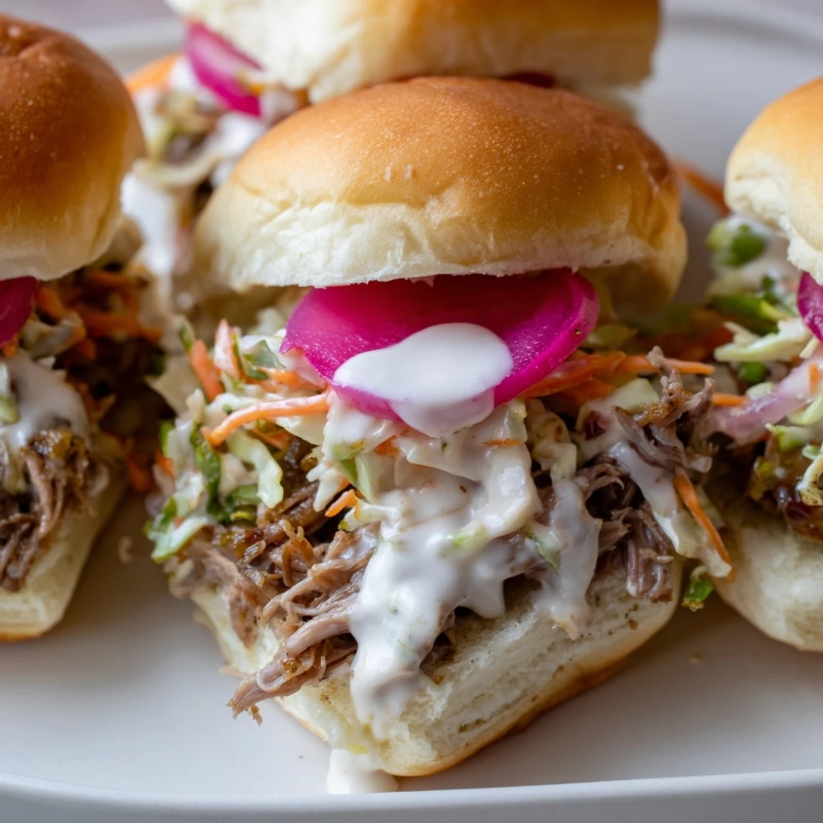 Creamy tangy sauce dripping down tender Alabama White Sauce Pulled Lamb Sliders with pickled onions