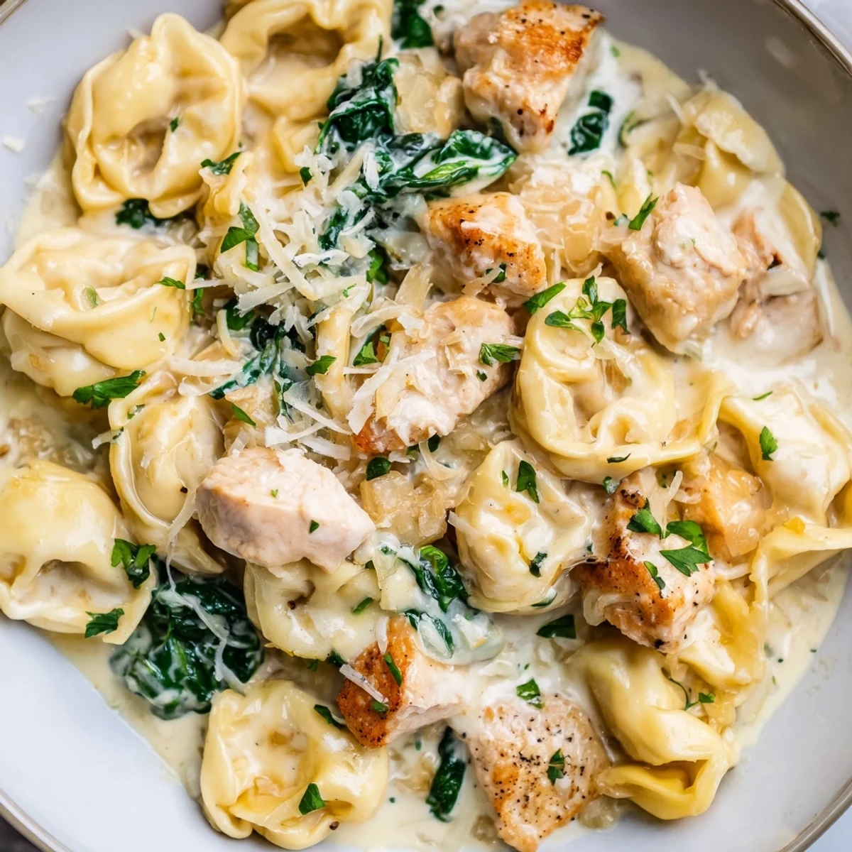 Cheesy tortellini tossed with tender chicken and wilted spinach in creamy garlic sauce