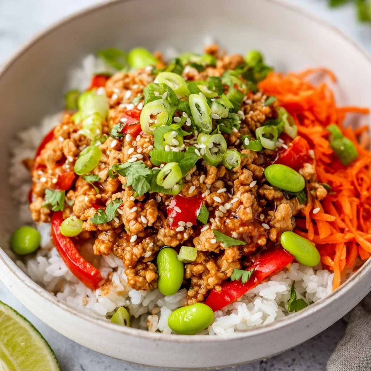 Steaming ground turkey rice bowls garnished with sesame seeds cilantro and lime wedges