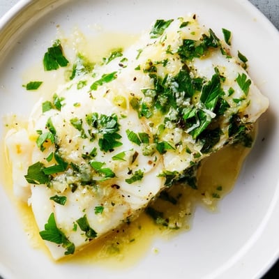 Flaky, tender Baked Halibut with Garlic and Lemon Butter served alongside vibrant green asparagus spears.